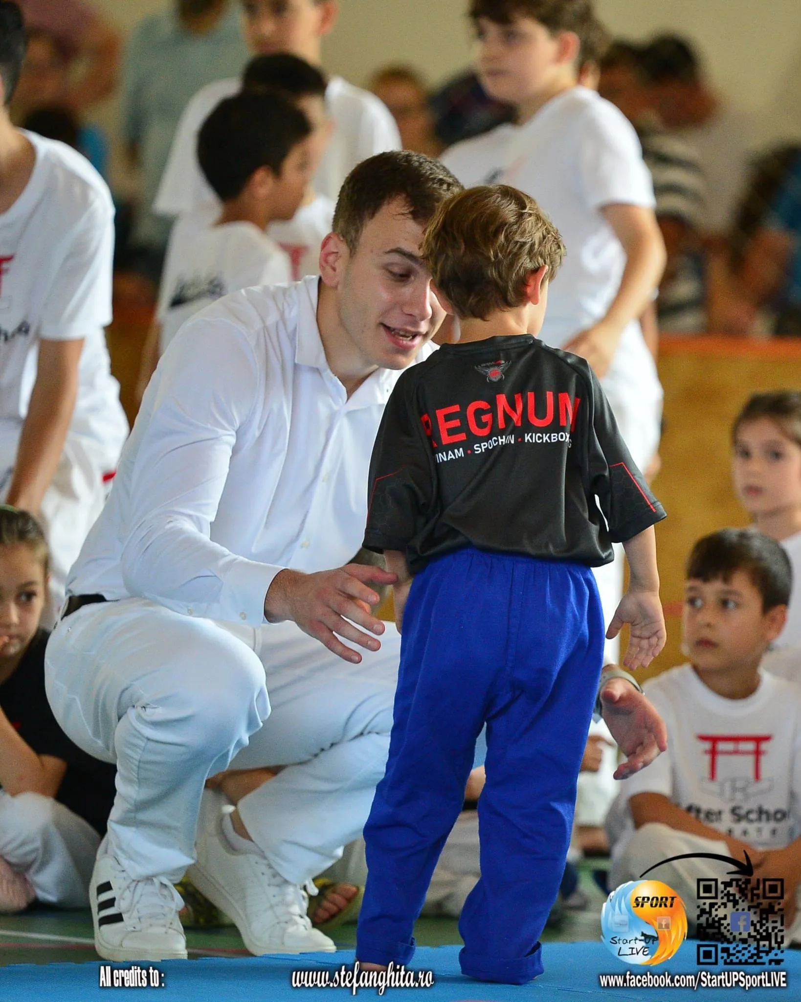 Antrenorul Regnum îi vorbește unui sportiv mic la o competiție